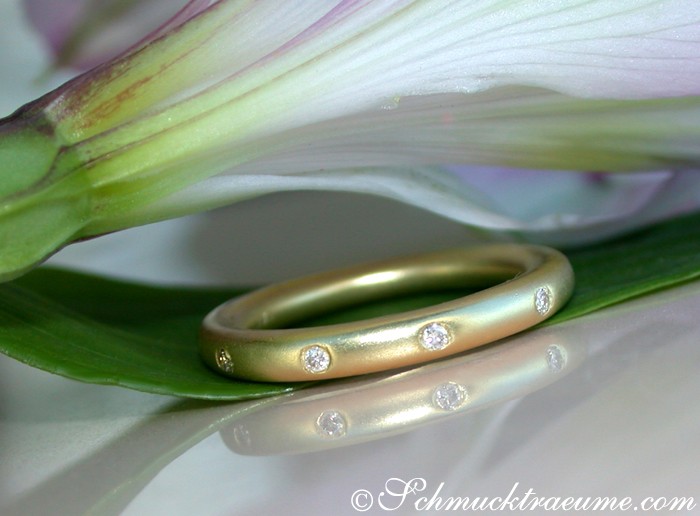 Gelbgoldring mit Diamanten im Sternenhimmel-Design, Detailaufnahme, zarte Blütenblätter im Hintergrund