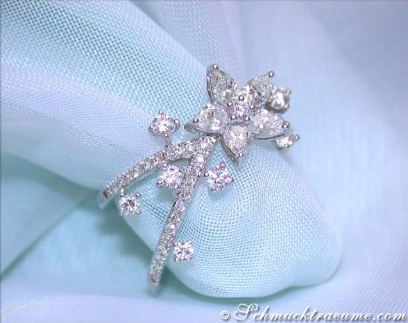 Weißgoldring mit Diamanten im Blüten-Design auf hellblauem Stoff.