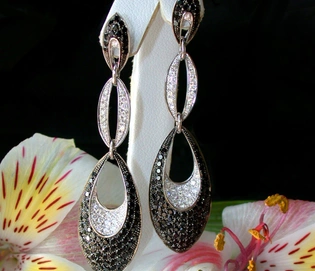 Schwarze & weiße Diamant-Ohrringe in Weißgold, elegant, modern, auf Blume präsentiert.