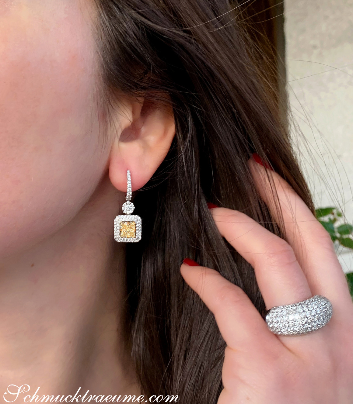 Gelbgold-Ohrringe mit gelben und weißen Diamanten, Detailaufnahme, getragen.