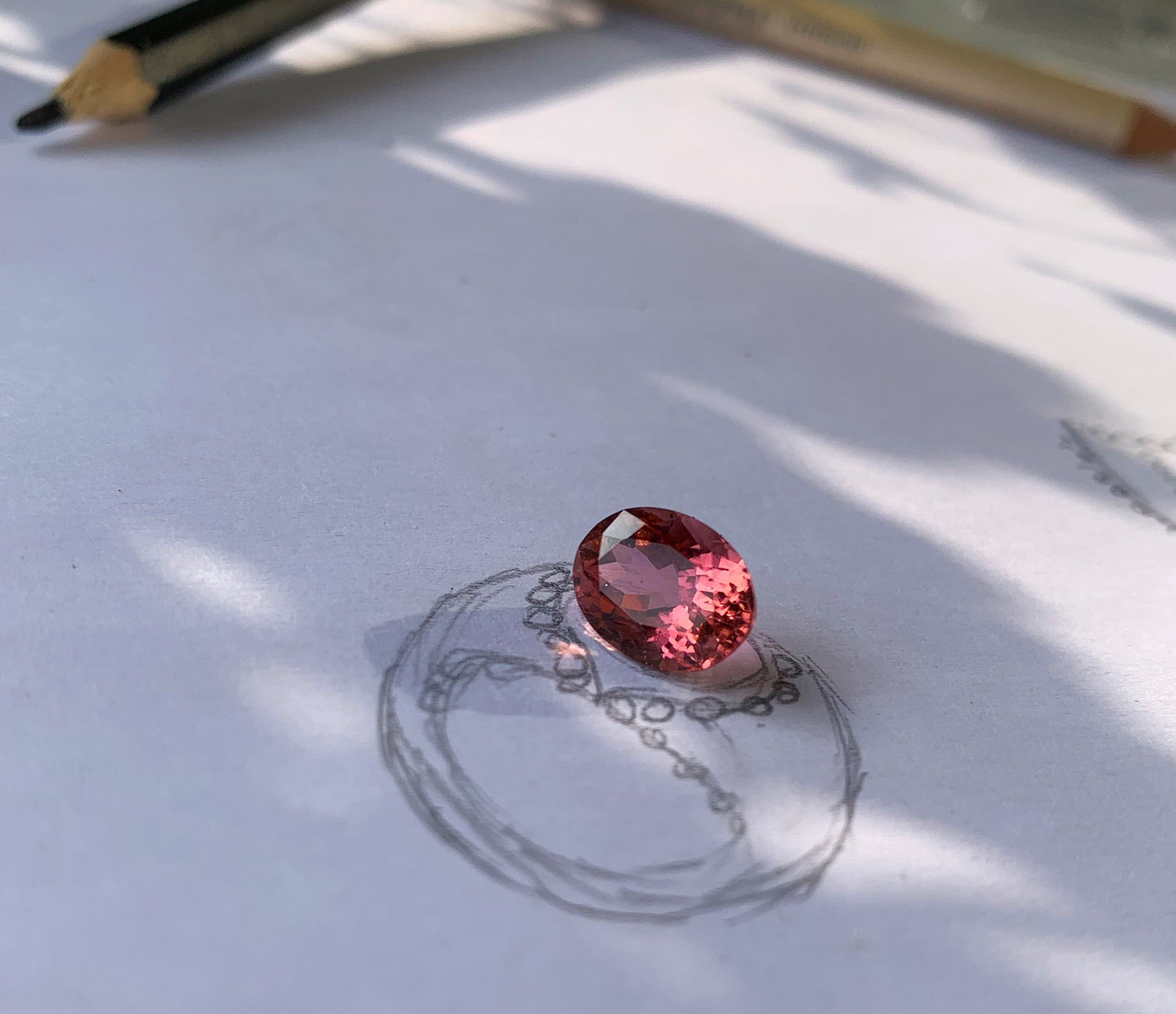 Rosa Turmalin Brillanten-Ring: Detailaufnahme, warme Farben, Schattenwurf, Bleistift im Hintergrund