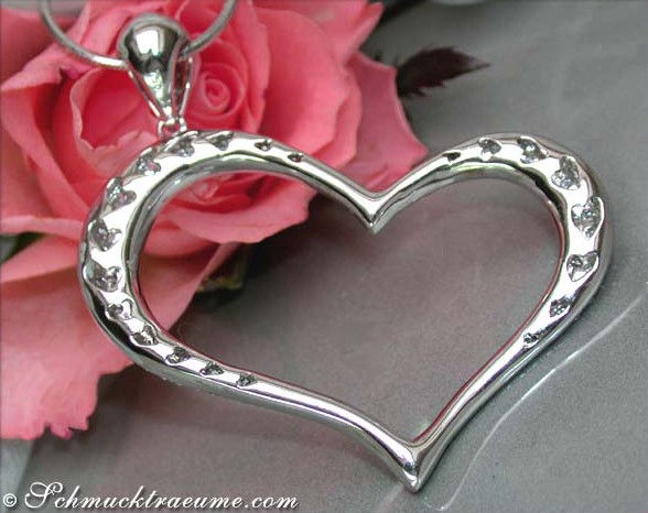 Silberner Herzanhänger mit Diamanten auf Rosenhintergrund