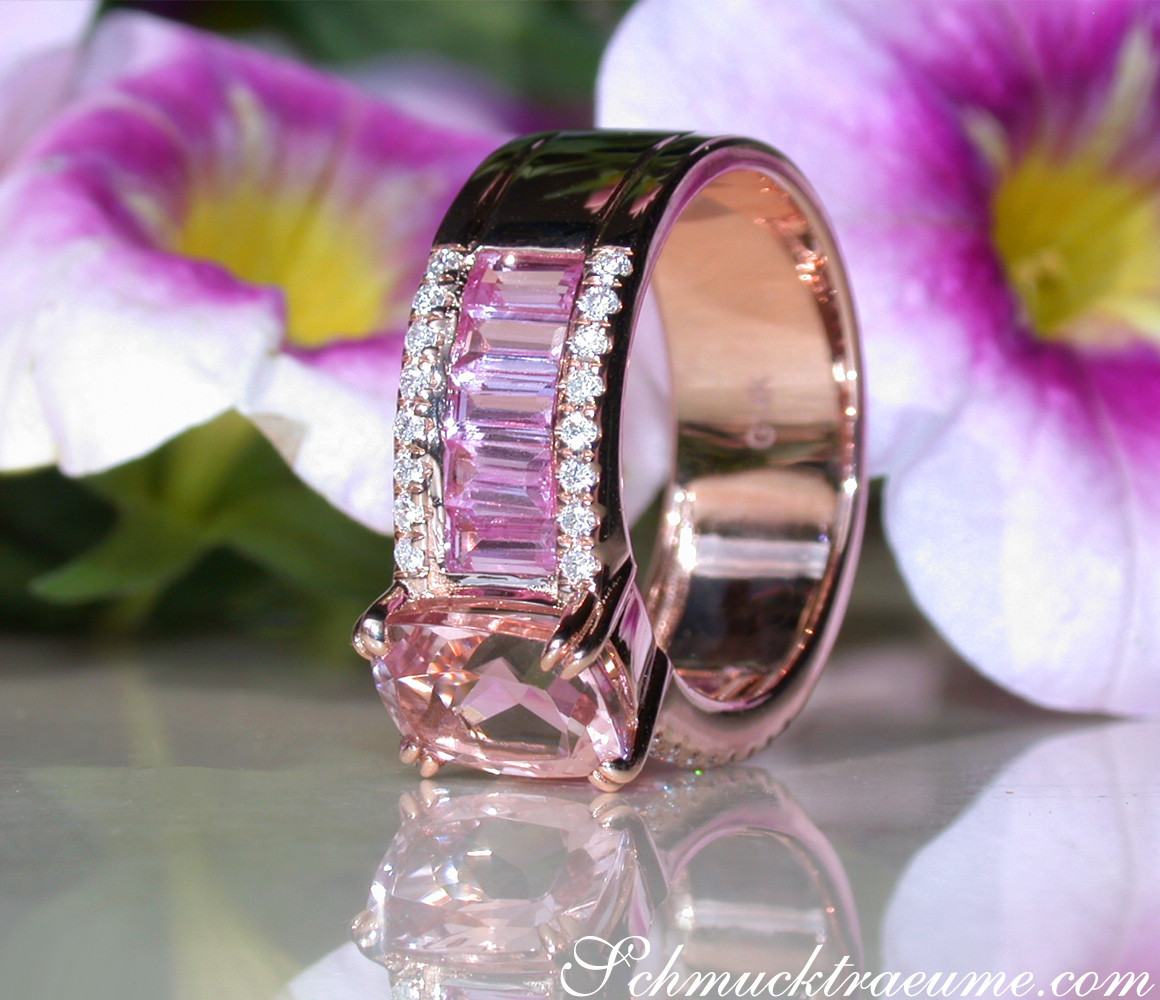 Pfirsichfarbener Morganit-Ring mit pinken Saphiren und Brillanten, vor Blütenblättern.