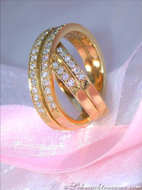 Detailansicht: Goldener Diamantring mit überkreuzten Strängen auf rosa Seide.