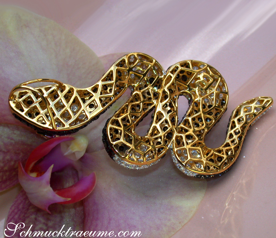 Goldener Schlangenanhänger mit Diamanten, filigran gearbeitet, auf Blüte liegend.