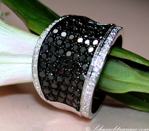 Schwarzer Diamantring auf Hand mit Blume, Detailaufnahme