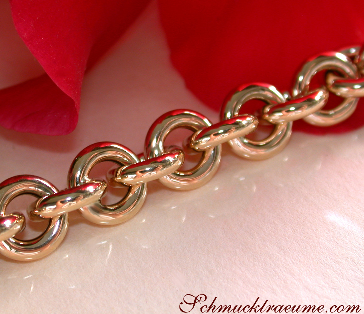 Goldarmband mit glänzenden Ringelementen auf rosa Untergrund