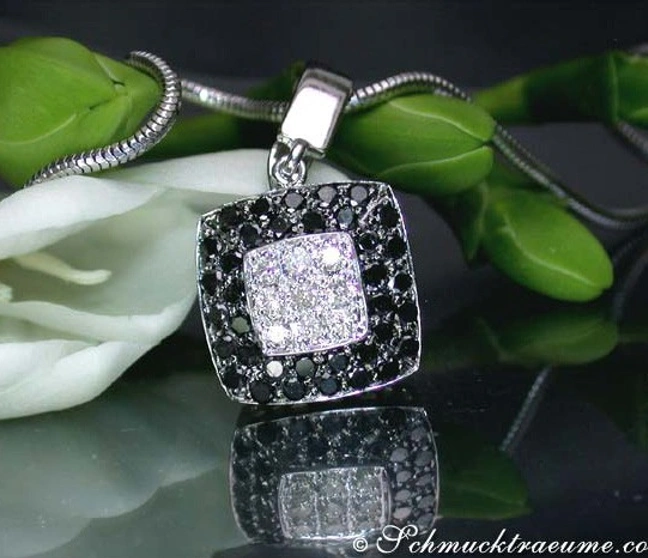 Silberner Carré-Anhänger mit schwarzen und weißen Diamanten, Detailaufnahme, vor grünem Blattwerk. Silberner Carré-Anhänger mit schwarzen und weißen Diamanten, Detailaufnahme, vor grünem Blattwerk.