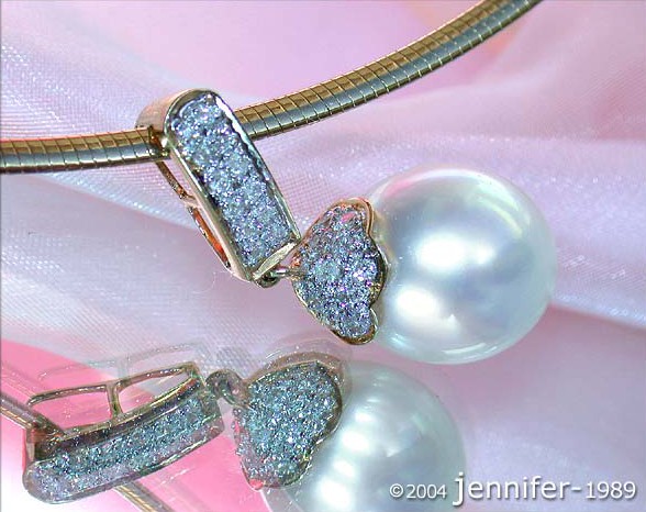 Detailansicht von Gelbgold-Anhänger mit Perle und Brillanten, auf rosa Stoff liegend