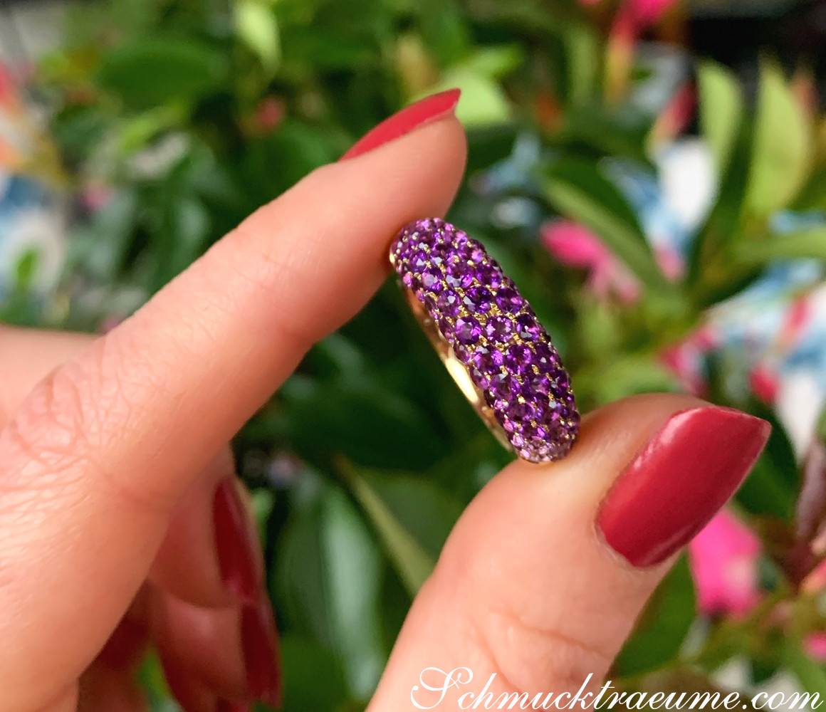 Amethyst Pavé Ring auf Hand vor grünem Hintergrund