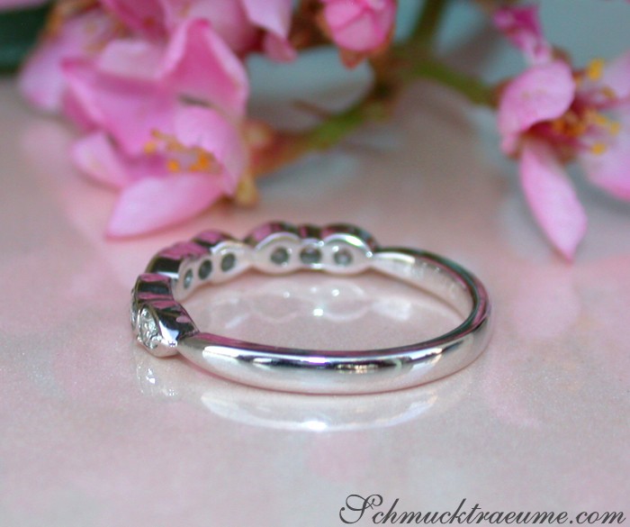 Weißgoldring mit Diamanten vor rosa Blüten.