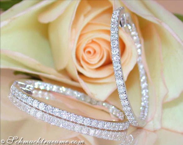 Weißgold Creolen mit Diamanten, detailreich, elegant, rosa Rose im Hintergrund.