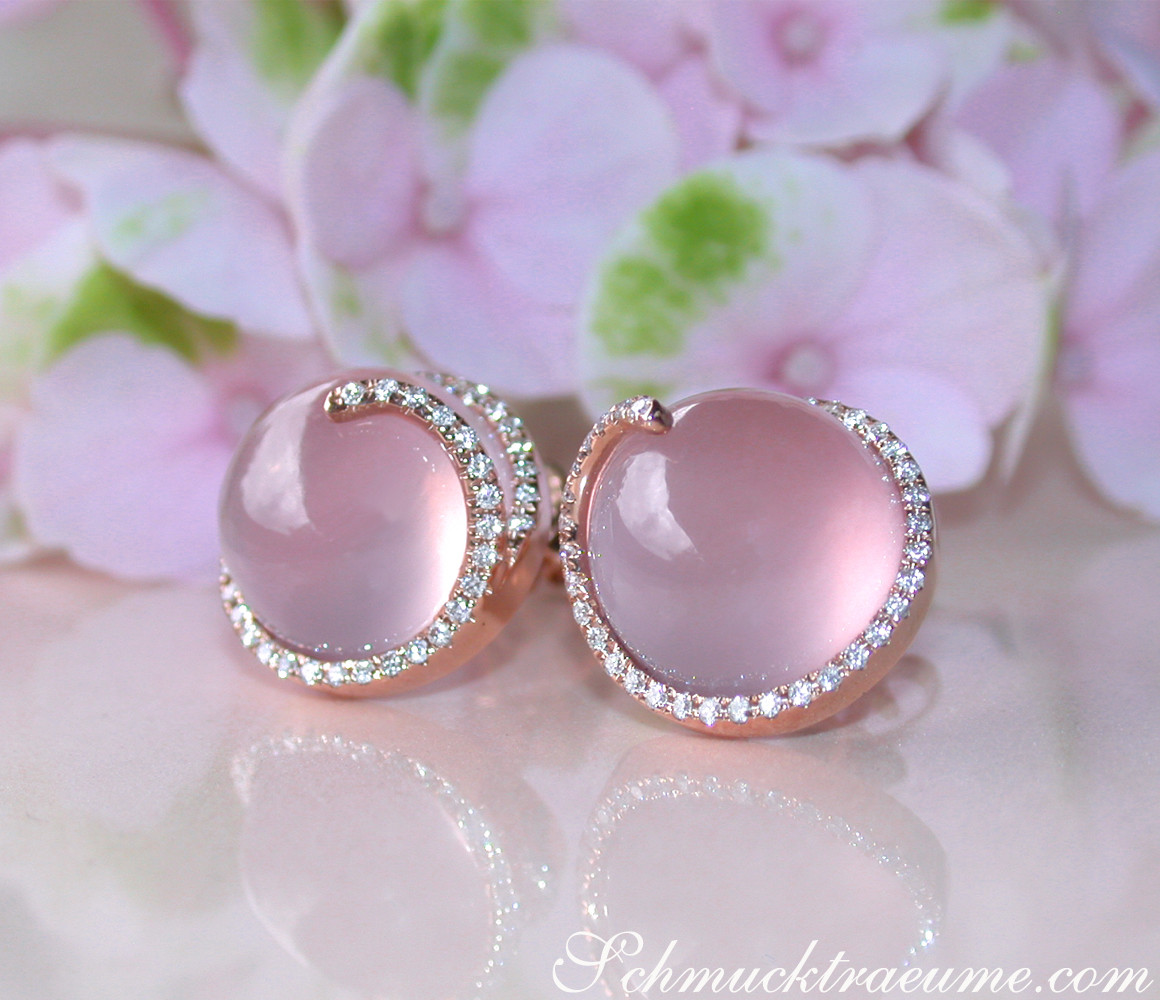 Rosenquarz-Ohrstecker mit Brillanten in Roségold 750, zart und elegant, auf rosa Blütenblättern.