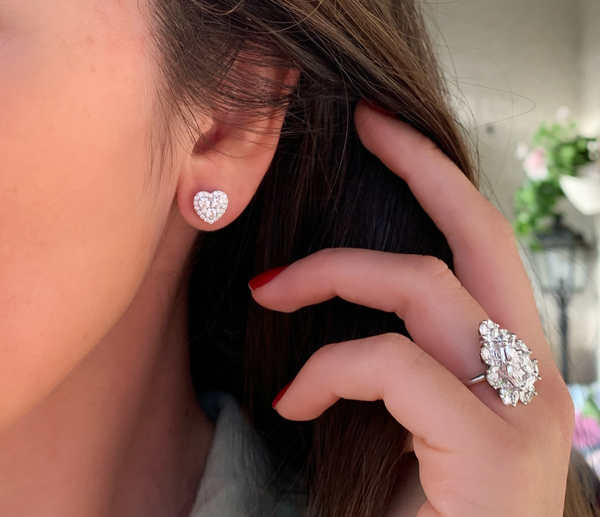 Herz-Ohrringe aus Weißgold 750 mit Diamanten, Detailaufnahme von Hand und Ohr.