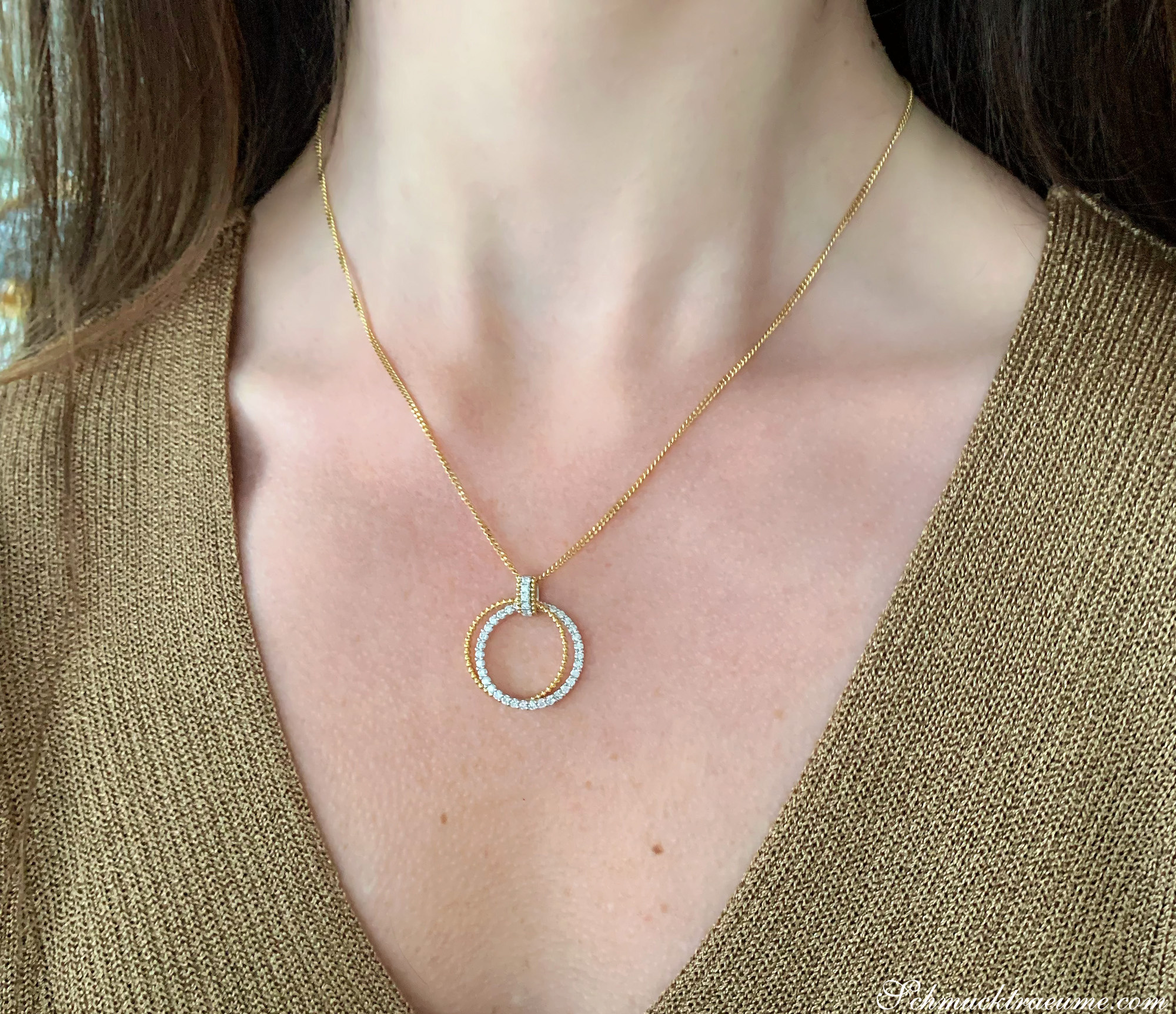 Kreisförmiger Anhänger aus Gelb- und Weißgold mit Brillanten, getragen über einem Pullover