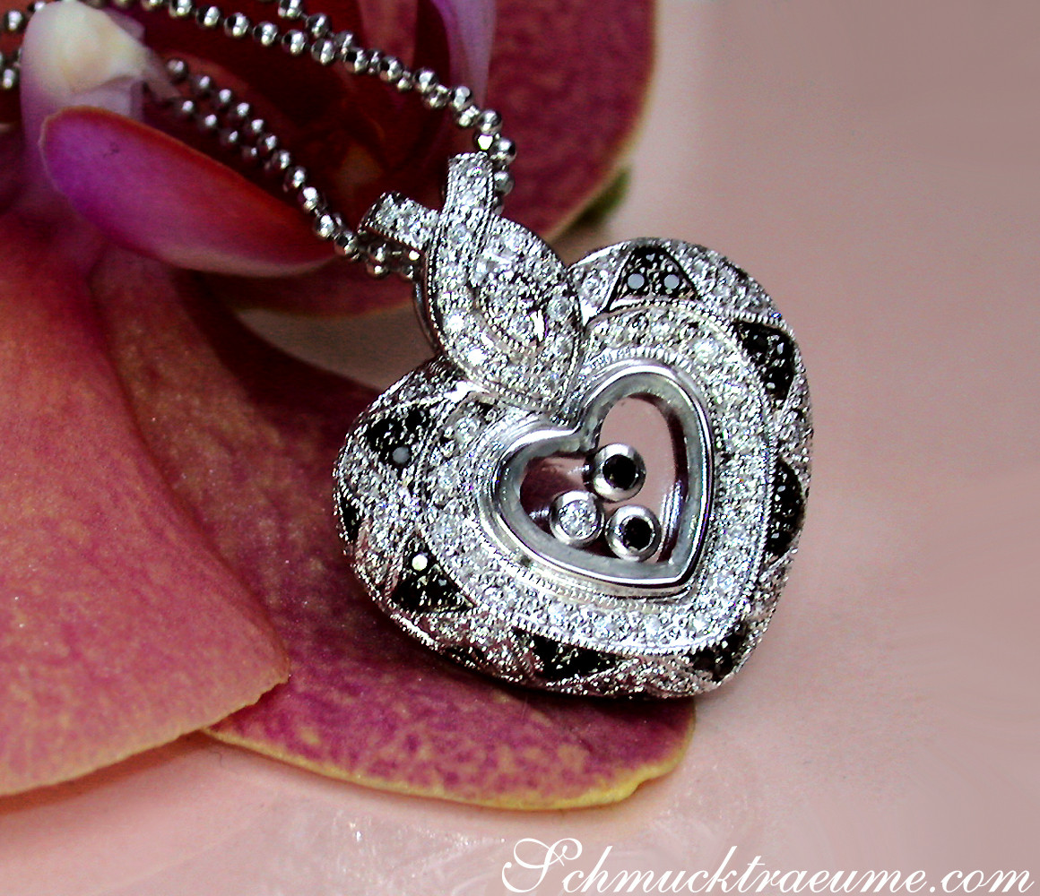 Herz-Anhänger mit schwarzen und weißen Diamanten, detailreich, in Hand gehalten.