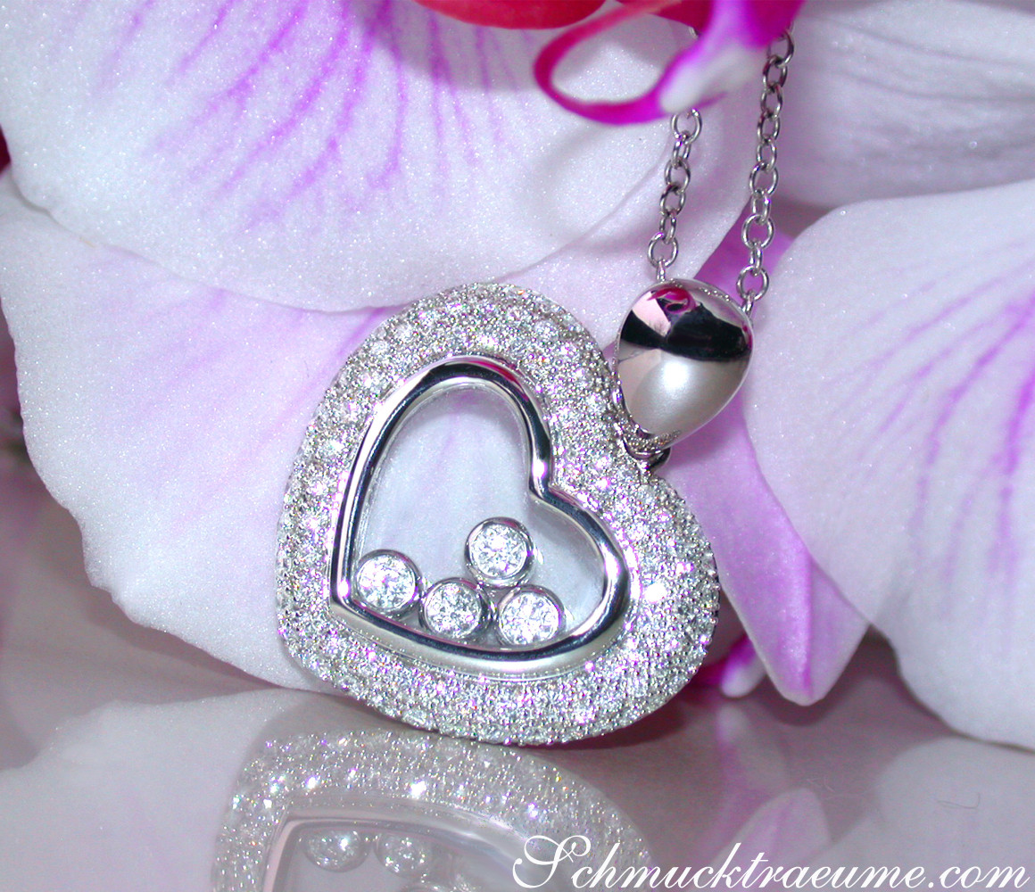 Glitzernder Herz-Anhänger mit Diamanten, verziert mit weißen Diamanten, vor Orchideenblüte.