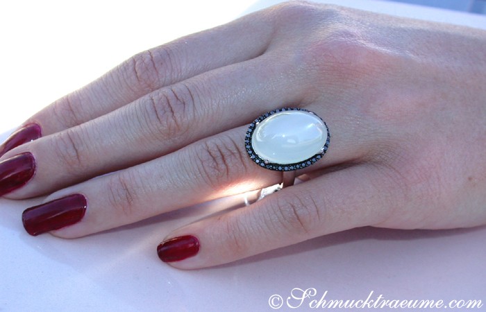 Detailansicht eines silbergrauen Mondstein-Rings mit schwarzen Diamanten, auf weißem Untergrund getragen