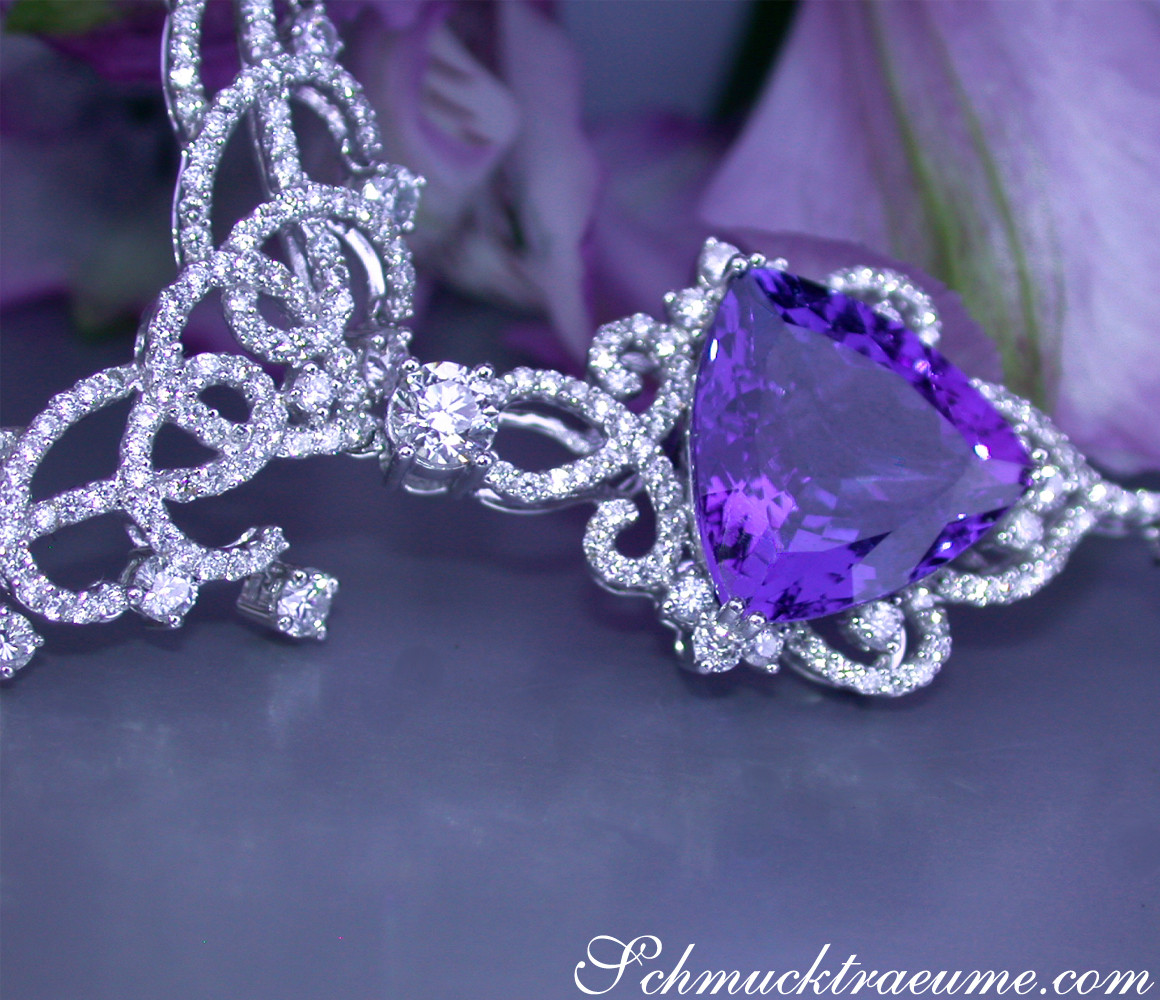 Weißgold-Collier mit großem Tansanit und Brillanten, Detailaufnahme, auf lila Blütenblättern liegend.