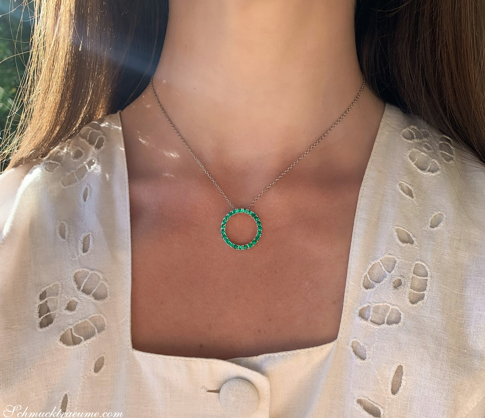 Klassischer Smaragdkreis-Anhänger mit feinen Linien und grünem Stein, getragen.