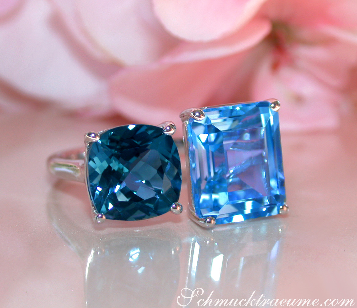 Klassischer Blautopas-Ring mit quadratischen Steinen auf Silber, vor rosa Blüte