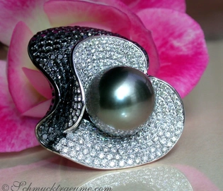 Schwarz-weißer Perlenring mit Diamanten, Detailaufnahme, rosa Blume im Hintergrund