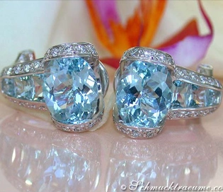 Aquamarin-Ohrstecker mit Brillanten auf Glanzfläche, Blüte im Hintergrund