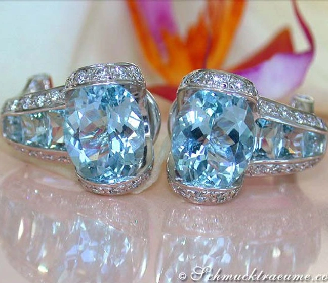 Aquamarin-Ohrstecker mit Brillanten auf Glanzfläche, Blüte im Hintergrund Aquamarin-Ohrstecker mit Brillanten auf Glanzfläche, Blüte im Hintergrund