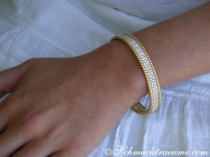 Goldener Brillantenarmreif auf weißem Ärmel, Detailaufnahme