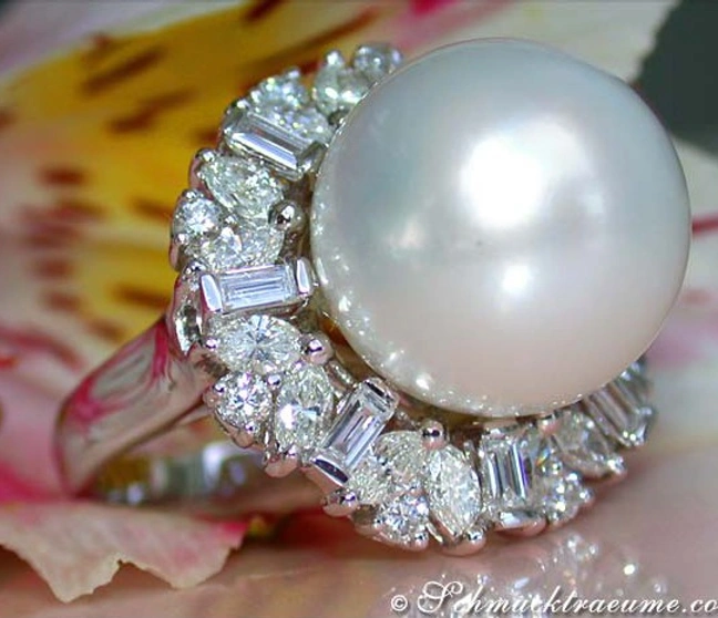 Perlenring mit Diamanten in Weißgold, Detailaufnahme, makellose Perle, Blumen im Hintergrund Perlenring mit Diamanten in Weißgold, Detailaufnahme, makellose Perle, Blumen im Hintergrund