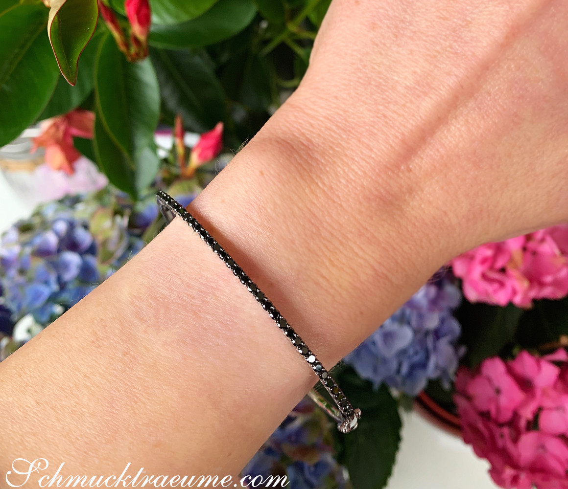 Armband mit schwarzen Diamanten auf Hand vor Blumen