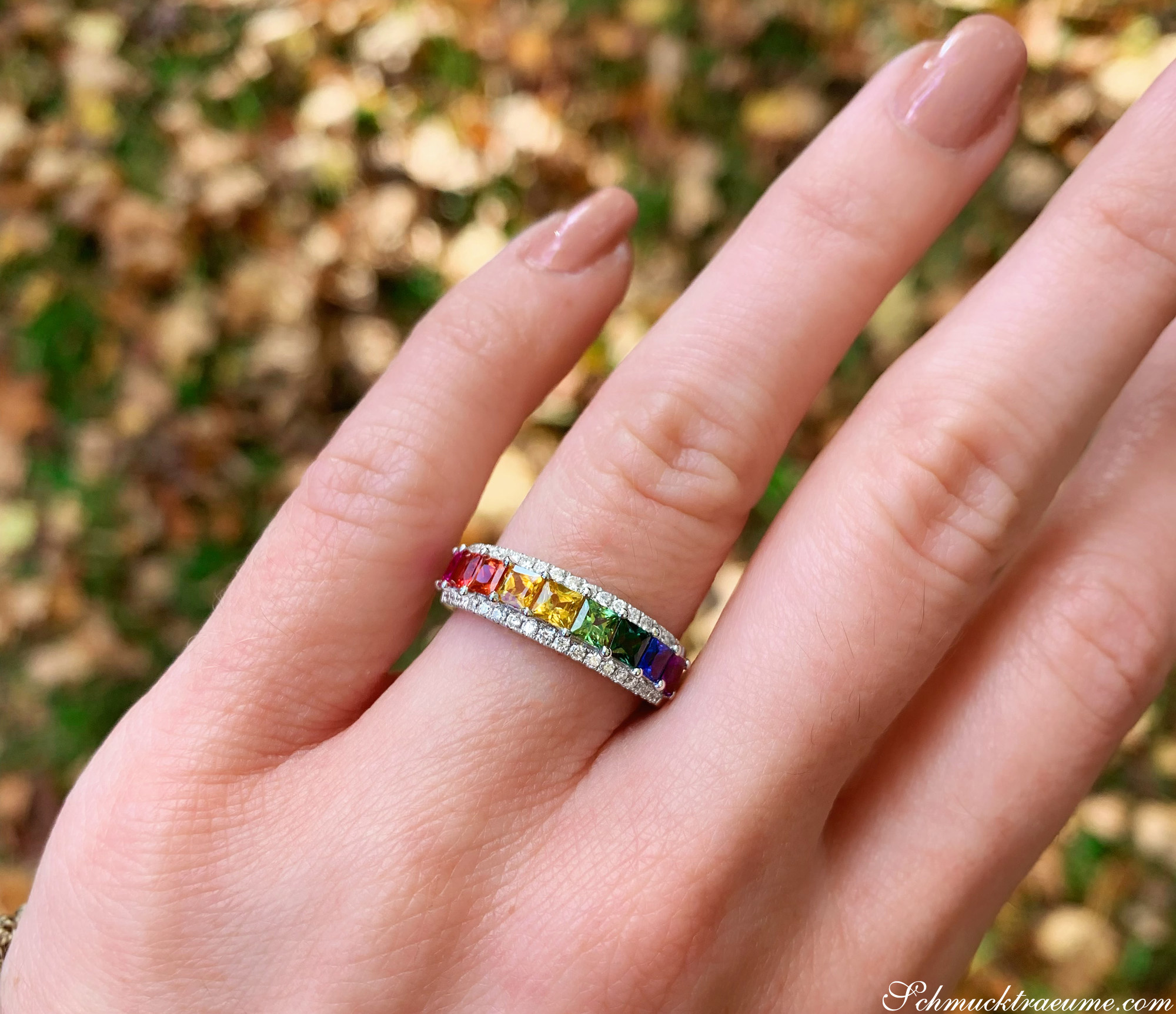 Regenbogen-Saphir-Ring mit Brillanten auf Hand vor Blättern
