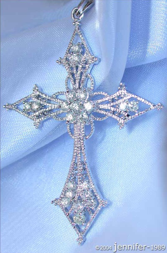 Weißgold Kreuzanhänger mit Diamanten, filigraner Design, Detailansicht auf blauem Stoff.