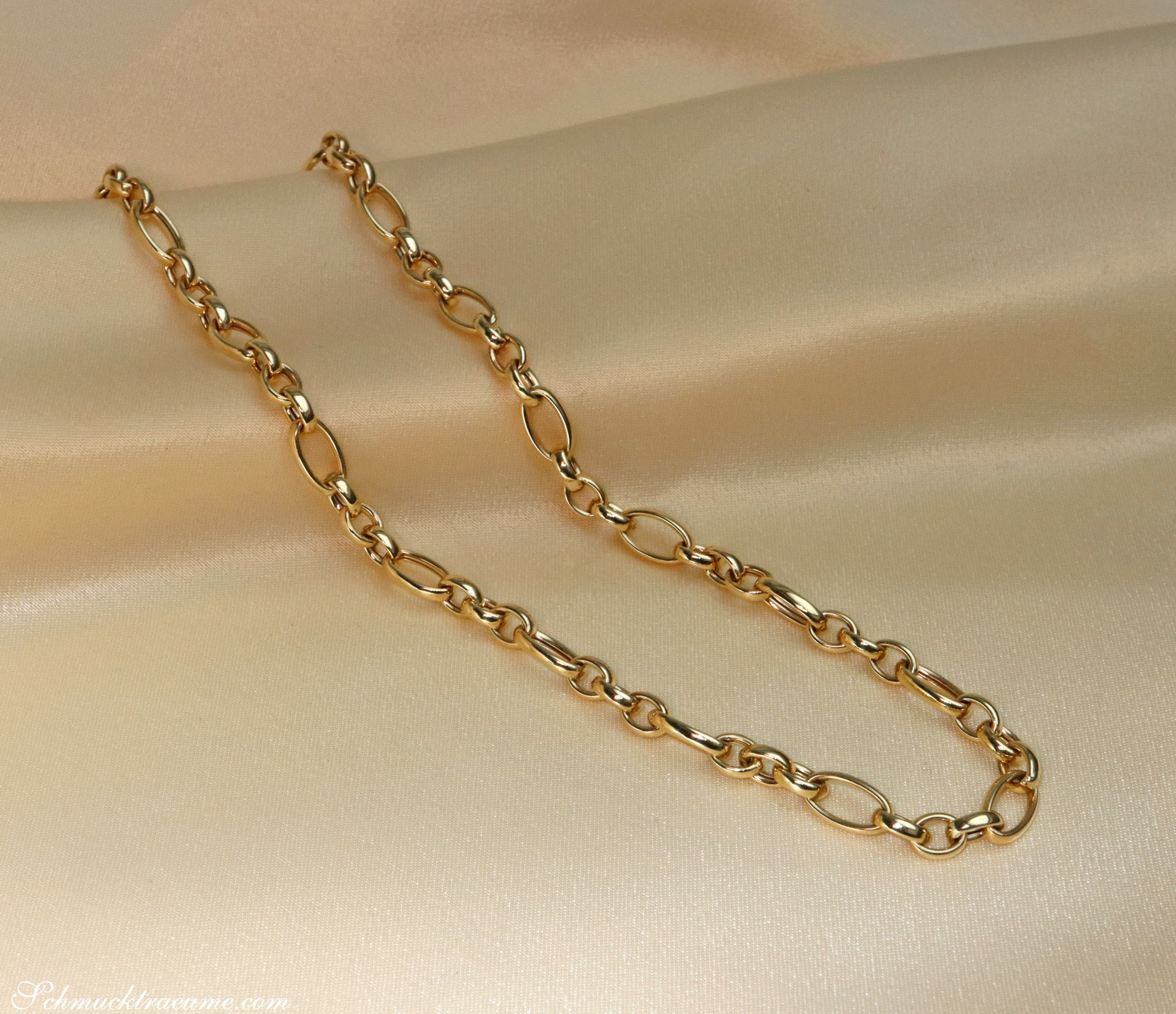Goldenes Glieder-Collier in 585er Gelbgold, elegant auf cremefarbener Stoffoberfläche liegend