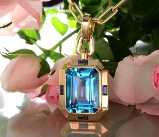 Goldener Blautopas-Anhänger mit Kettenhalsband, umgeben von Rosenblättern.