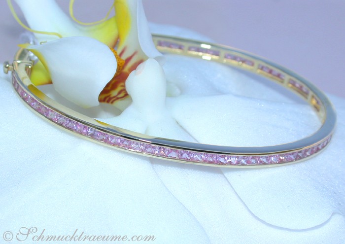 Edler rosa Saphir-Armreif in Gelbgold, Detailaufnahme, elegant auf Blume präsentiert