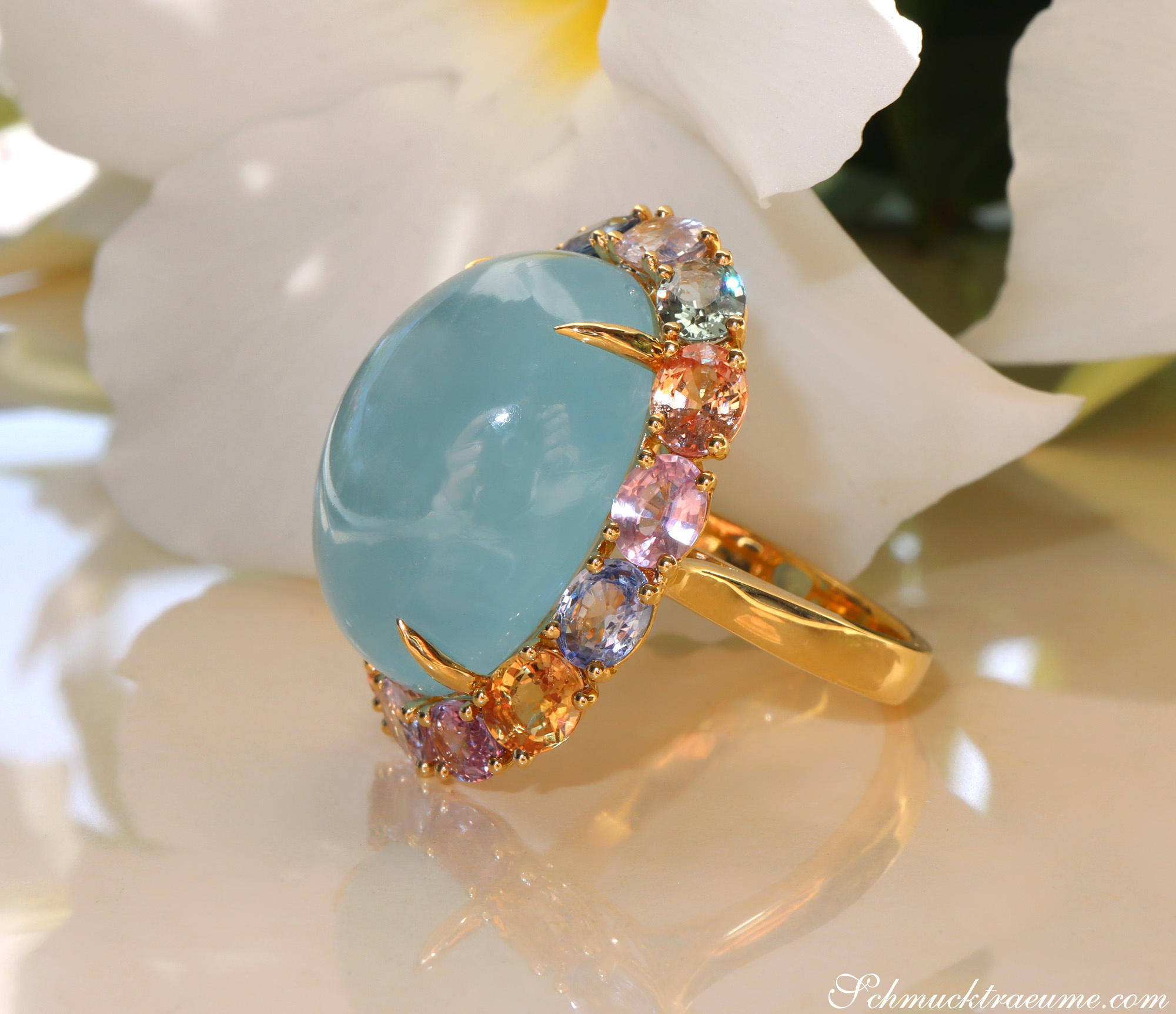Goldener Ring mit Aquamarin und Multicolor Saphiren, detailreich, auf Blüte abgebildet.