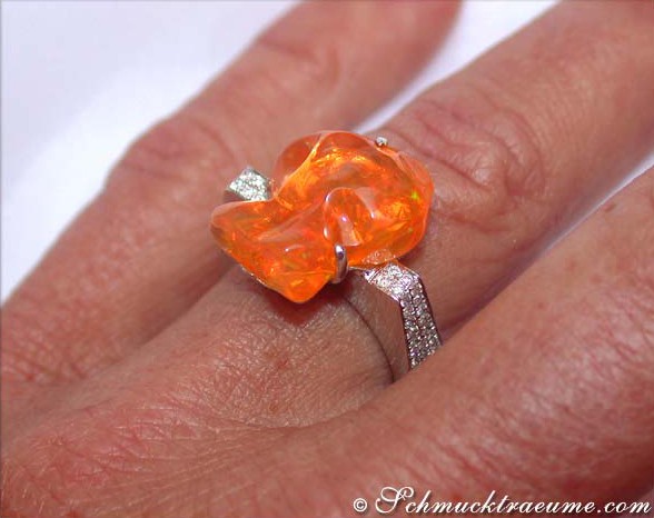 Weißgoldring mit orangefarbenem Feueropal und Diamanten, Detailaufnahme auf Handfinger.