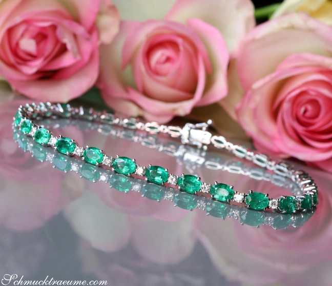 Smaragd-Armband mit Brillanten auf Rosenblüten-Hintergrund Smaragd-Armband mit Brillanten auf Rosenblüten-Hintergrund