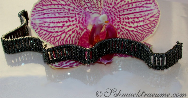 Schwarzrhodiniertes Weissgold-Armband mit 410 Diamanten, Detailaufnahme, Orchideenblüte im Hintergrund