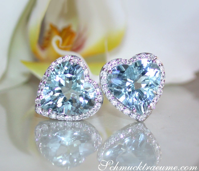 Herzformige Aquamarin-Ohrstecker mit Diamanten in Weißgold 585, zarte Farbtöne, Orchidee im Hintergrund. Herzformige Aquamarin-Ohrstecker mit Diamanten in Weißgold 585, zarte Farbtöne, Orchidee im Hintergrund.
