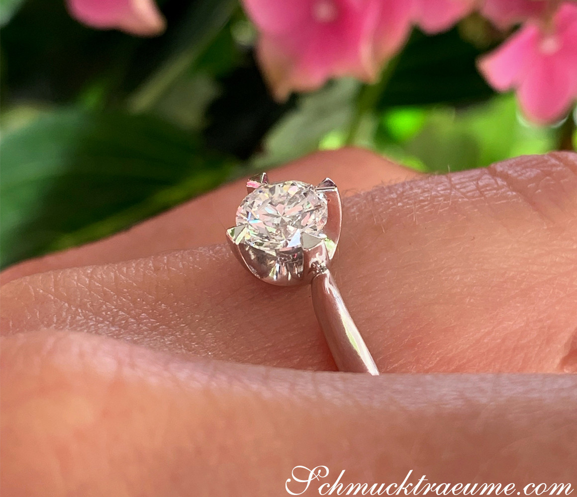 Weißgold-Ring mit großem Brillant auf blühendem Hintergrund