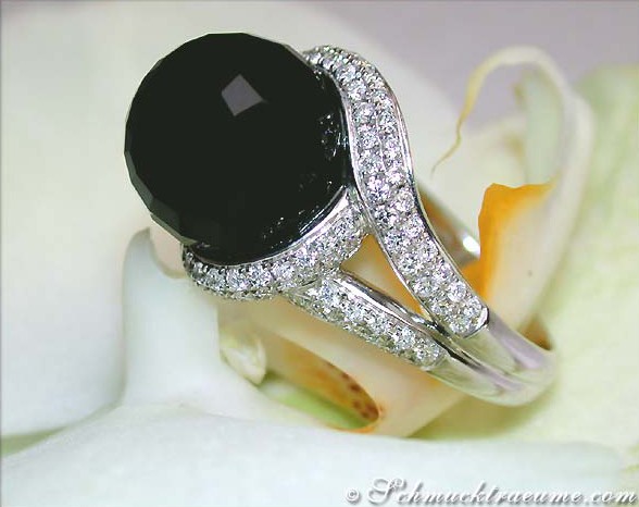 Onyx-Ring mit Brillanten auf weißem Blütenhintergrund