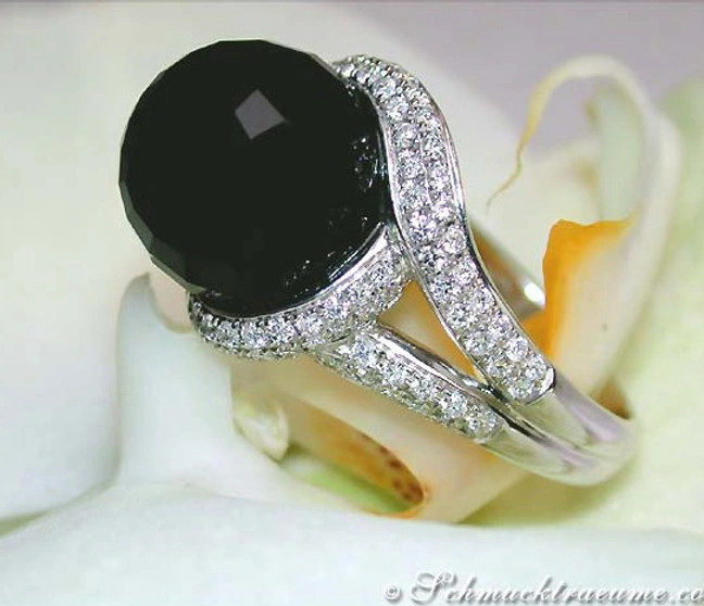 Onyx-Ring mit Brillanten auf weißem Blütenhintergrund Onyx-Ring mit Brillanten auf weißem Blütenhintergrund