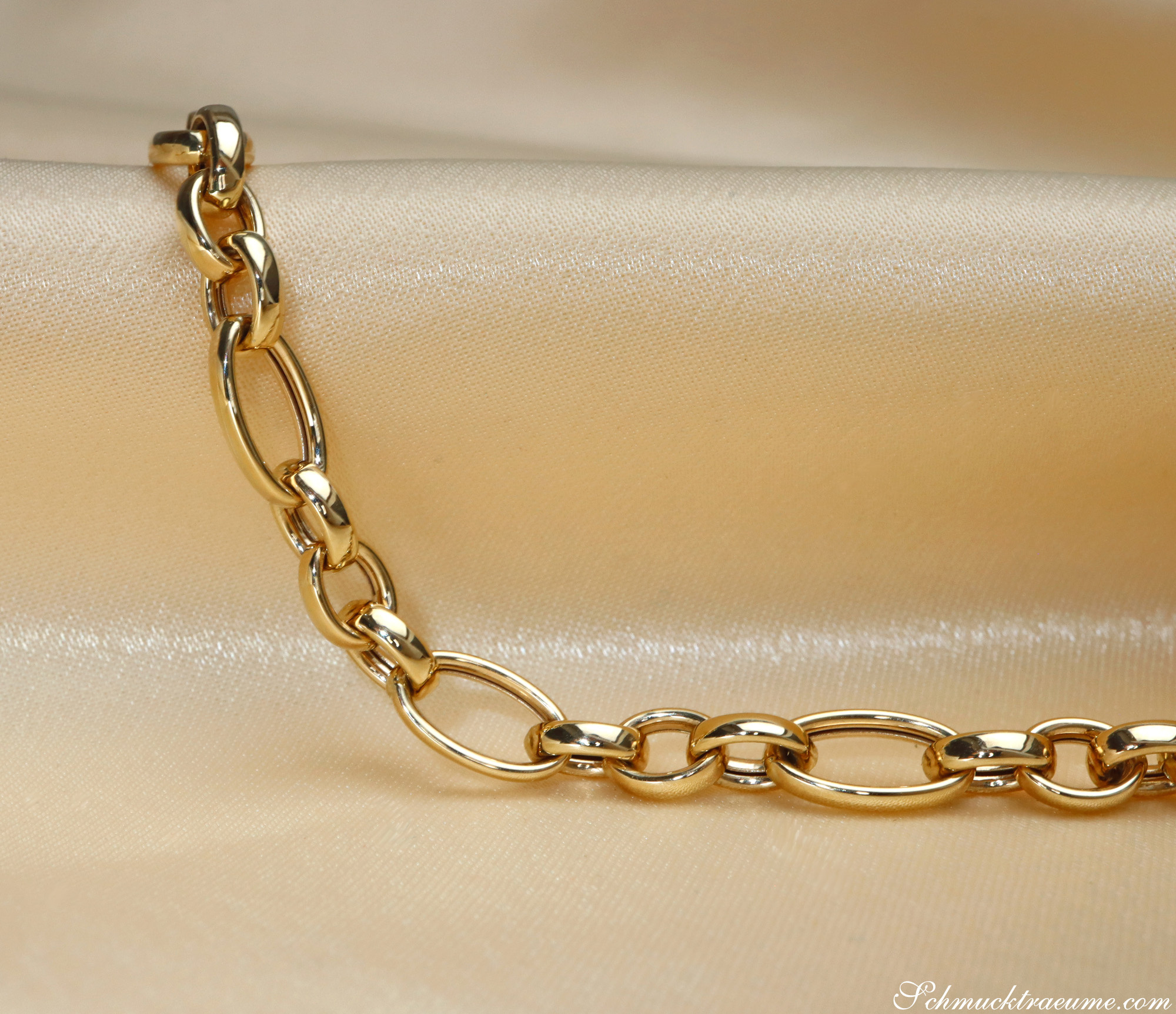 Goldene Gliederkette aus Gelbgold 585, detailreich, auf cremefarbenem Stoff liegend