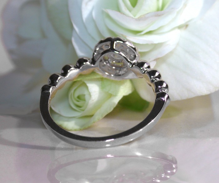 Weißgoldener Ring mit Diamanten und Kugel-Design, Detailaufnahme auf Rosenblatt liegend