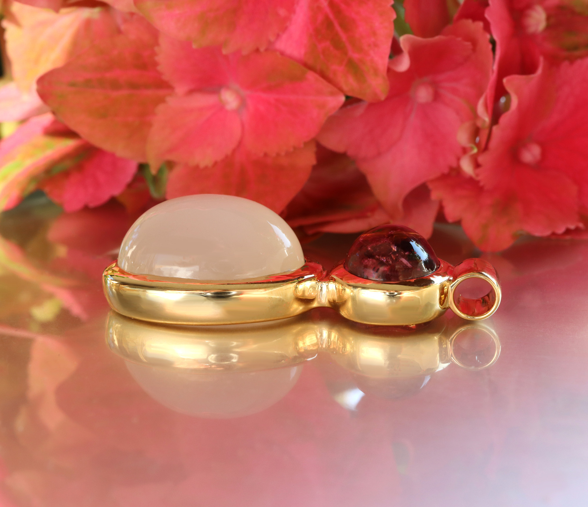 Rubellit-Mondstein-Collier mit handverlesenen Farbedelsteinen, sanfte Linien, Gelbgold 750, vor Blütenhintergrund