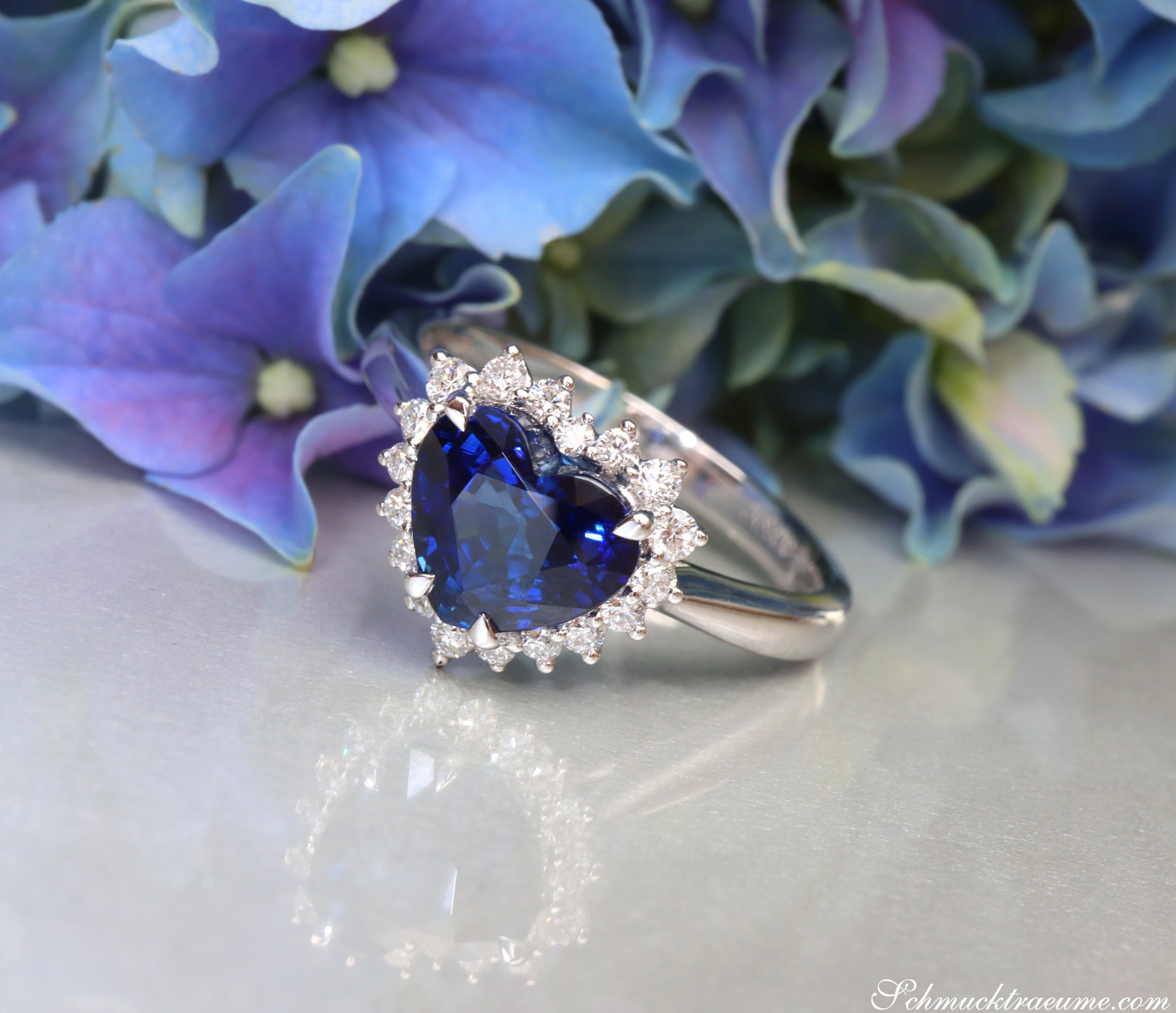 Blauer Saphir Herzring mit Brillanten auf Blumenhintergrund