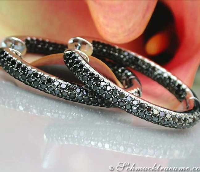 Schwarze Diamant-Creolen in ovaler Form, detailreich, auf weißem Hintergrund. Schwarze Diamant-Creolen in ovaler Form, detailreich, auf weißem Hintergrund.