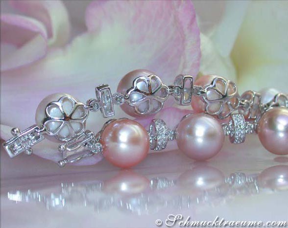 Perlenarmband mit Diamant-Blumenanhängern, Detailaufnahme, rosa Hintergrund.